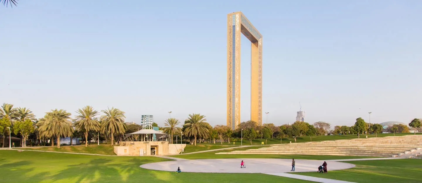Green lawns and palm trees at Zabeel Park with Dubai Frame in the background